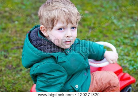 Little todder boy playing with big toy car