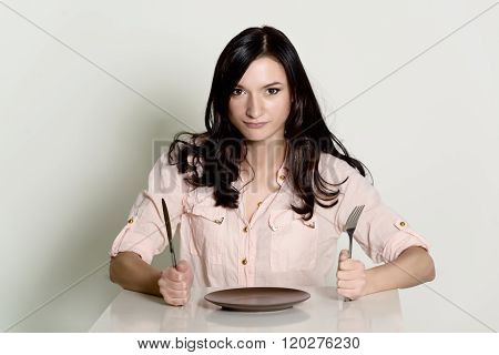 dissatisfied brunette woman waiting for a meal on an empty plate. white backgruond
