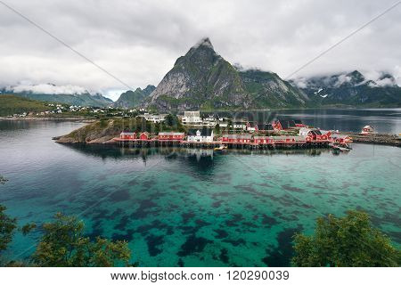 Scenic fjord on Lofoten islands with typical red fishing hut and towering mountain peaks