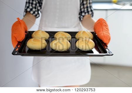 Woman Holding Hot Roasting Pan With Hot, Freshly Baked Bread Rolls