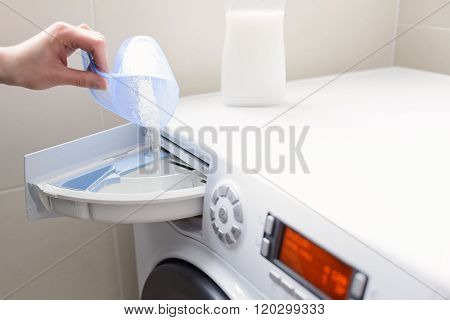 Closeup On Woman's Hand Pouring Detergent Into The Washing Machine