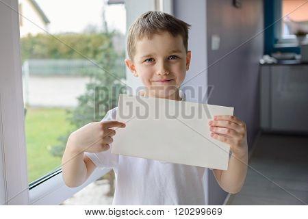Happy Boy In A Polo Shirt, Holding An Empty Copyspace Sheet Of Paper