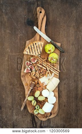 Wine appetizers set: cheese selection, honey, grapes, almonds, walnuts, bread sticks, figs on olive