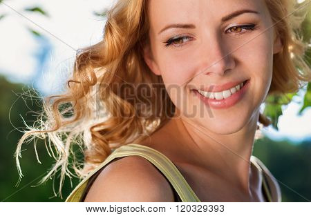 Blond woman, flipping curly hair. Sunny summer nature.