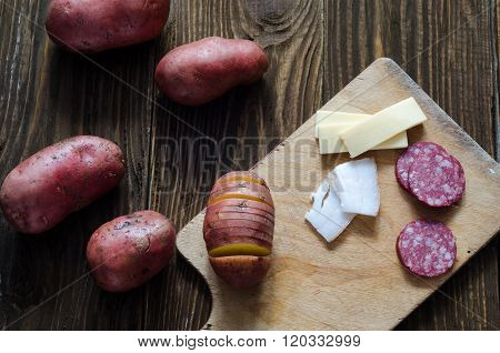 Raw potatoes, sousage, lard, cheese on wooden background