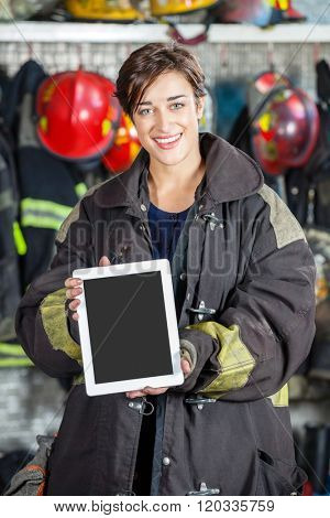 Confident Firewoman Showing Digital Tablet At Fire Station