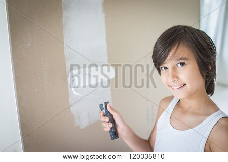 Little cute boy painting on a wall