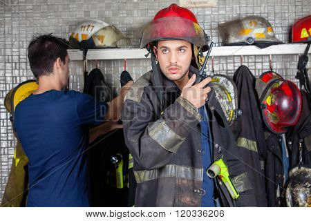 Firefighter Using Walkie Talkie With Colleague In Background