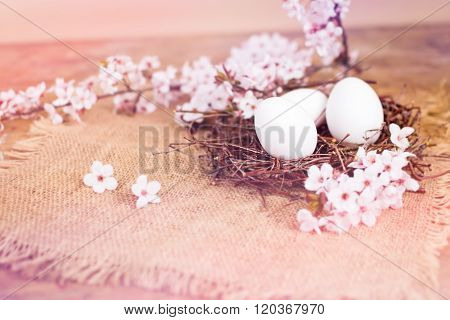 Pink spring flowers and white Easter eggs in nest
