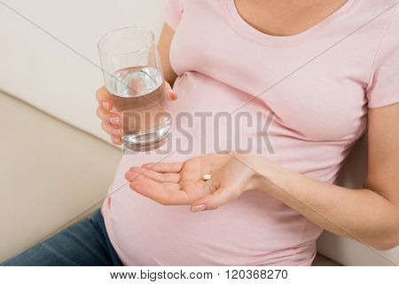 Pregnant Woman Hand With Glass Of Water And Vitamin Pill