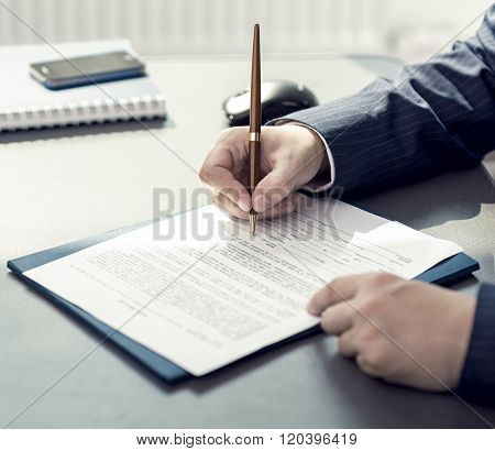 Financial planner signing annual report in company's office