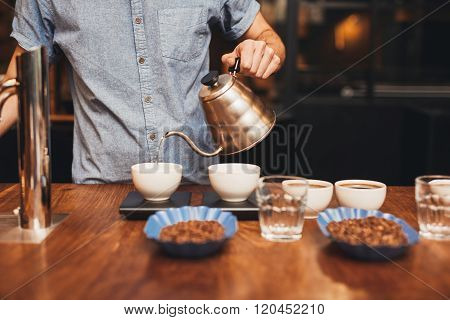 Man pouring water into coffee cup on a digital scale