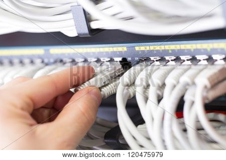 IT consultant connects a network cable into switch in datacenter