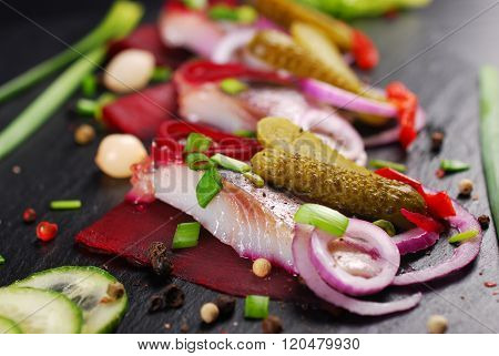 Herring Appetizer With Beets And Gherkin On Black Slate Board