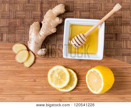 Fresh ginger root lemon and honey on wooden cutting board natural remedy.