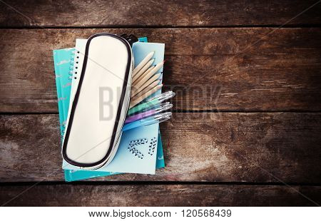 Pencil case with various stationery on old  wooden table