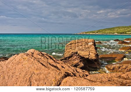 Red rocks and turquoise water at beach in San Pietro island, Sardinia
