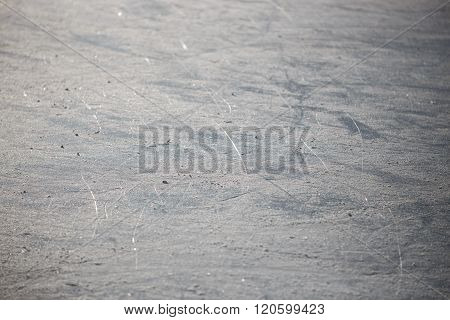 Bad ice at the city rink in sunny spring day. Many bands, cuts, cracks