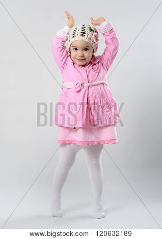 Little Girl Is Standing On Her Tiptoe And Raising Her Hands In The Air, She Is Wearing Pink Cloths A