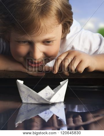 boy play in paper ship in water puddel