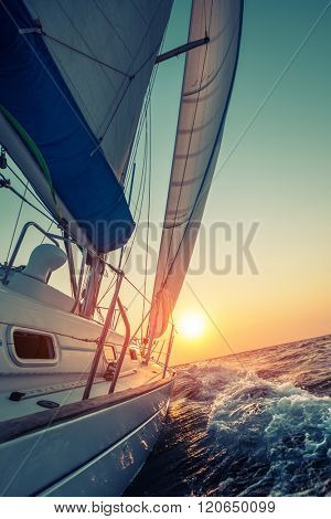 Sail boat moving in the open sea at sunset