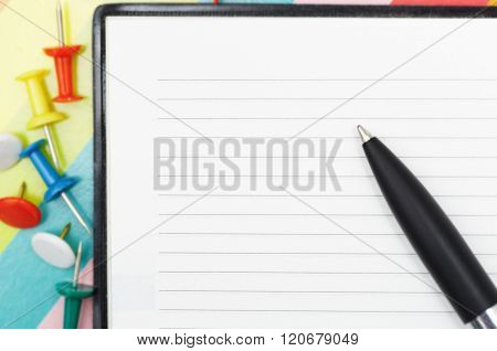 Notepad with pen and pushpins. Close-up photo