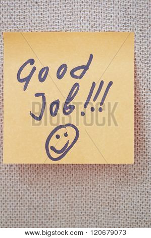 Adhesive note with Good Job text on a cork bulletin board