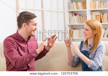Smiling young woman talking using sign language with her hearing impairment man