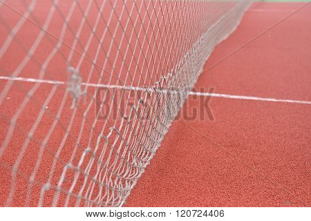 Detail Of Net Tennis On Field Made From Red Granule Rubbe. Selective Focus