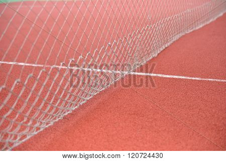 Detail Of Net Tennis On Field Made From Red Granule Rubbe. Selective Focus