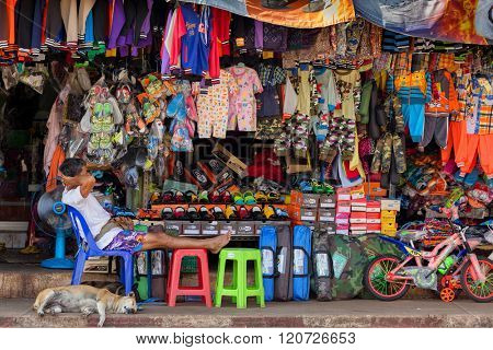THONG PHA PHUM, THAILAND, JANUARY 23, 2016 : A man and his dog are lying asleep under the heavy sun in the street clothes store in Thon Pha Phum, Thailand