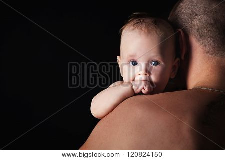 Young Happy Family In The Studio On A Dark Background In Dark Clothes Holding A Baby On The Hands An
