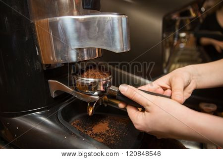 equipment, coffee shop, people and technology concept - close up of woman making coffee by machine at cafe bar or restaurant kitchen