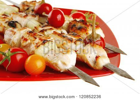 fresh grilled chicken shish kebab served wtih tomato cherry hot peppers on skewers over red plate isolated on white background