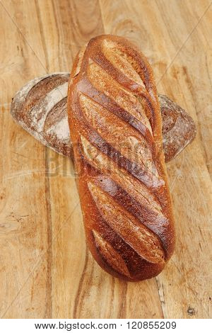 different rye and white flour french bread loaf with on light wooden table background