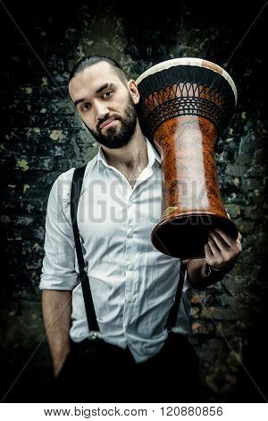 Handsome man posing in white shirt holding hand drum