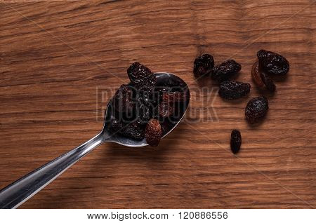 Risins On Metal Spoon On Brown Wooden Table