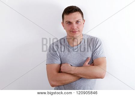 Happy young man. Portrait of handsome young man in casual shirt keeping arms crossed and smiling while standing against white background