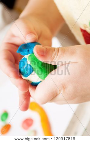Child moulds from modeling clay on table. hands with modeling clay. Little girl is learning to use colorful play dough
