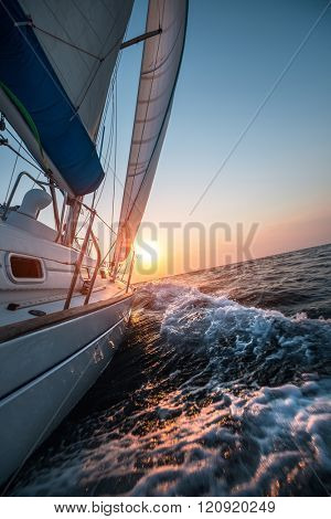 Sail boat moving in the open sea at sunset 