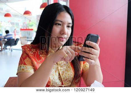 Woman In Red And Golden Chinese Costume Using Mobile Phone