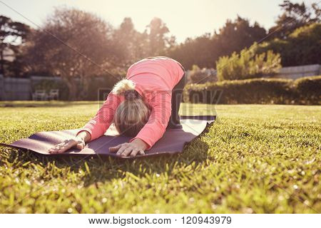 Senior woman doing yoga outdoors in gentle morning sunlight