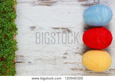 Easter eggs wrapped woolen string and green cress on wooden background, copy space for text, decorat