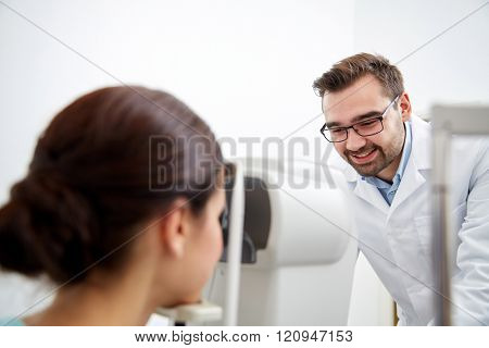 health care, medicine, people, eyesight and technology concept - optometrist with non contact tonometer checking patient intraocular pressure at eye clinic or optics store