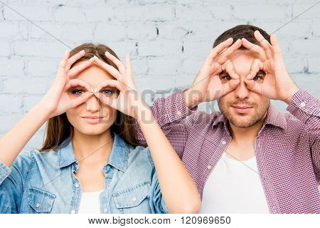 Portrait Of Comic Couple Holding Hands Near Eyes Like Glasses