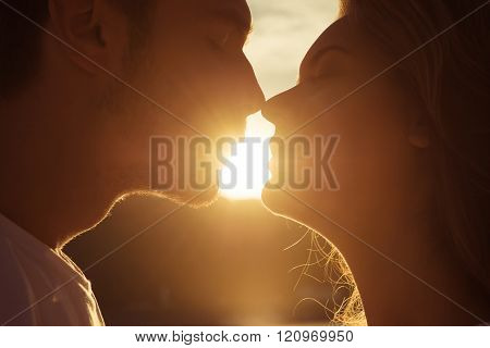 Close Up Portrait Of Two Young Lovers Kissing On The Sunset