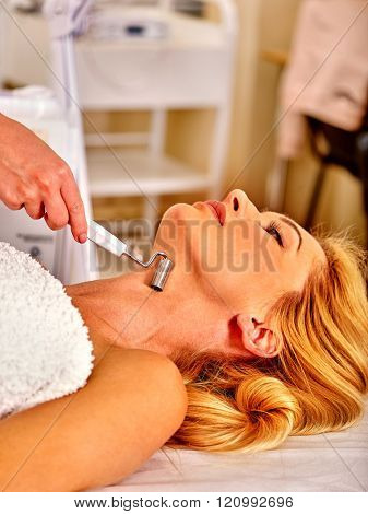 Young woman enjoying electric galvanic neck spa massage at beauty salon. 