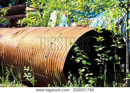 A rusty culvert laying in a scape metal yard.