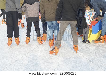 Ice skating teenagers on the skating rink in orange ice skates.