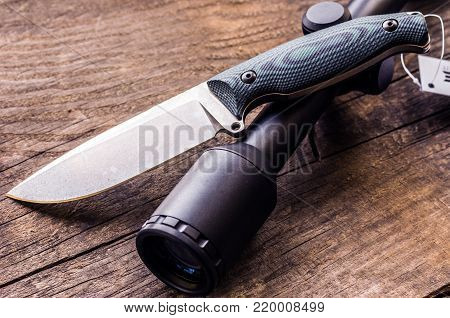 Hunting composition. Hunting knife and optical sight. Background from an old tree.